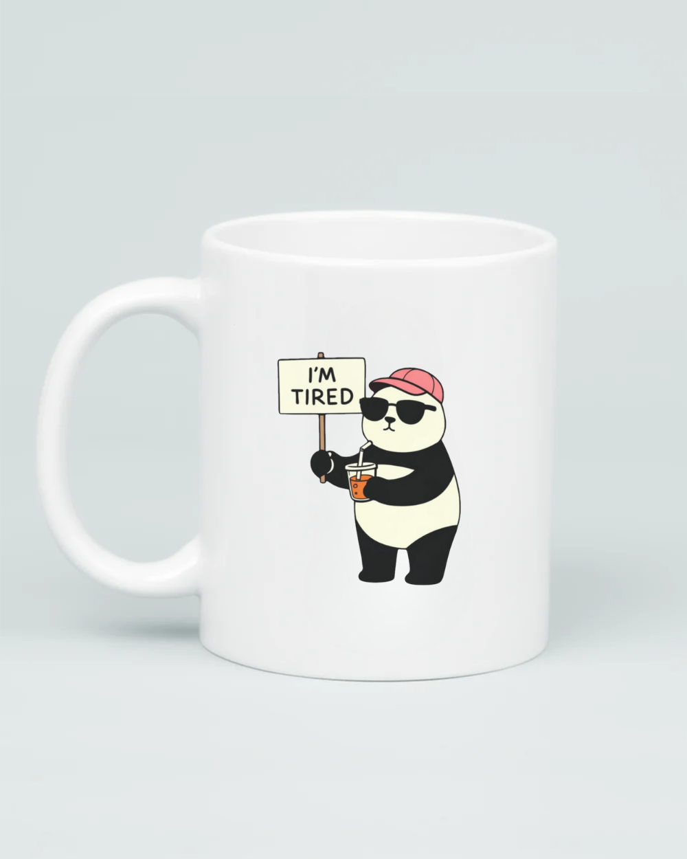 White coffee mug featuring a cartoon panda wearing sunglasses and a pink hat, holding a coffee and an 'I'm Tired' sign, on a clean grey background.